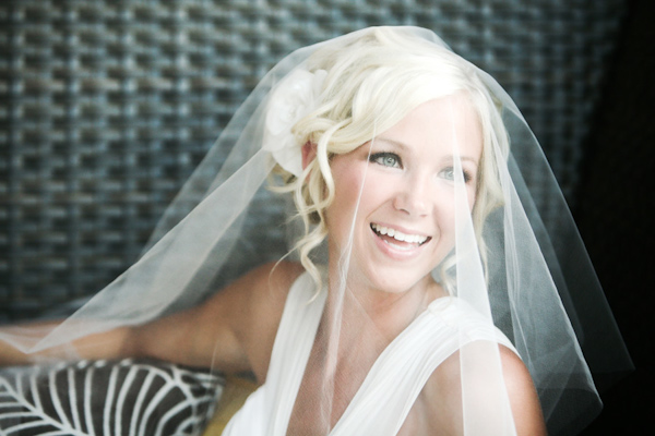 beautiful bride with hair in updo with soft spiral tendrils framing her face and wearing a white floral hairpiece and elbow length veil draped over her face - wedding photo by Jennifer Bowen Photography